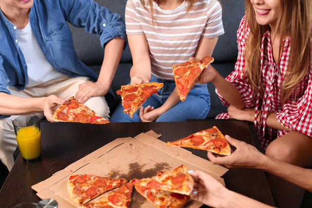 Молоді люди розважаються на вечірці зі смачною піцою в приміщенні
 - Фото, зображення