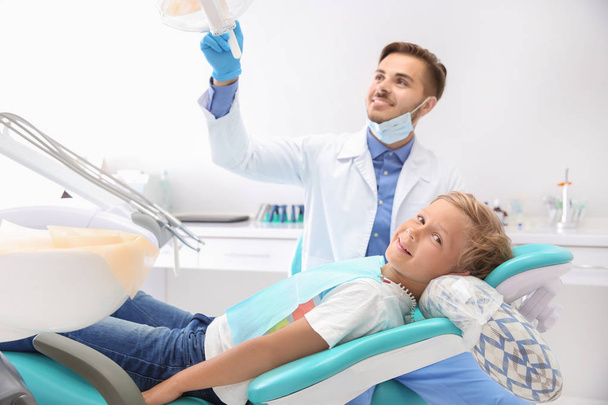 Dentista che esamina i denti del bambino in clinica - Foto, immagini