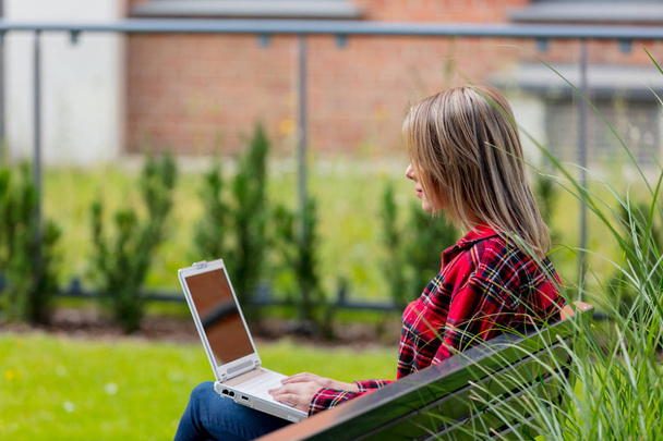 Portrait de jeune femme travaillant en ligne assis sur un banc
 - Photo, image