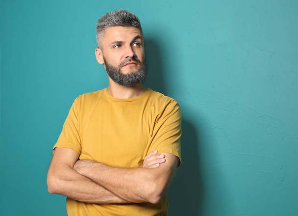 Portrait of handsome man with dyed hair and beard on color background - 写真・画像