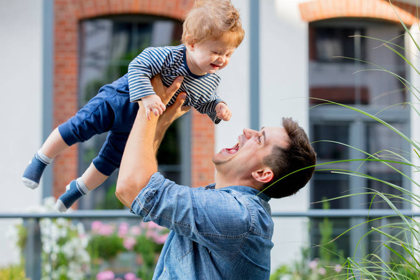 Junger Vater spielt mit Sohn im Freien nahe Haus. - Foto, Bild