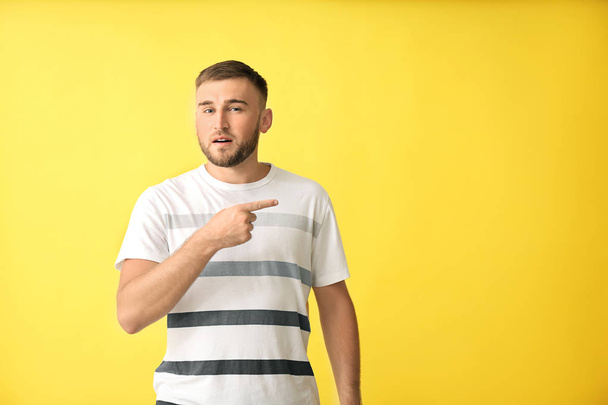 Handsome man pointing at something on color background - Photo, Image
