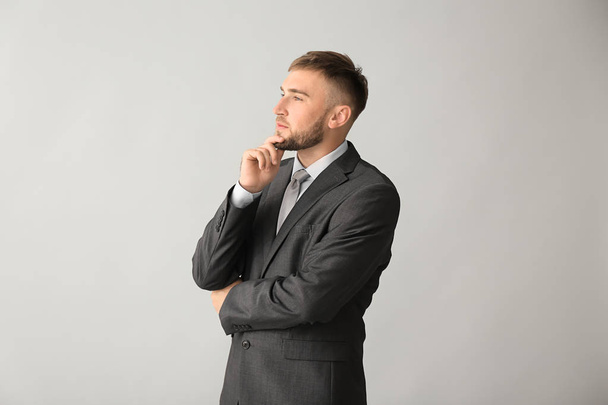 Thoughtful businessman on grey background - Фото, изображение