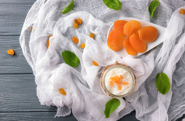 Glass jar with delicious rice pudding and dry apricots on gauze cloth - Fotografie, Obrázek
