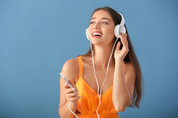 Beautiful young woman listening to music on color background - Photo, image