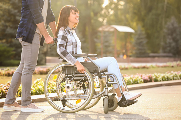 Jovem mulher em cadeira de rodas e seu marido ao ar livre
 - Foto, Imagem