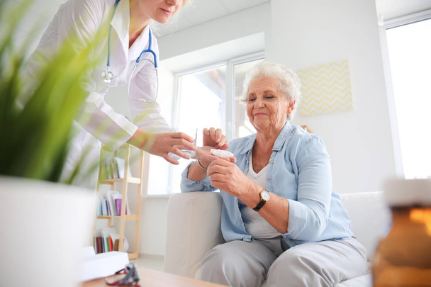 Doctor giving medicine to senior woman at home - Fotoğraf, Görsel