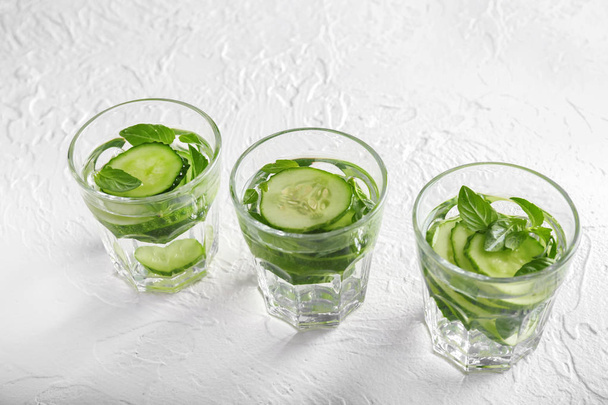 Glasses of cucumber infused water on white textured background - Foto, Bild