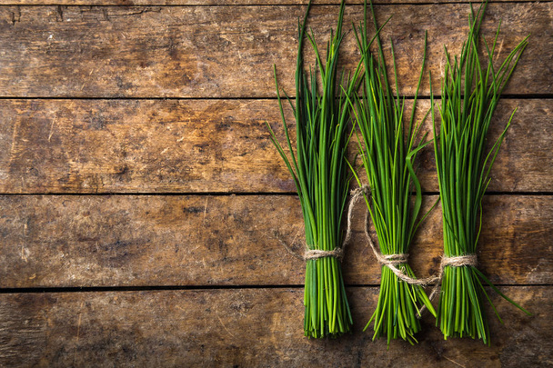 fresh chives on wooden rustic background, top view, copy space - Foto, Bild
