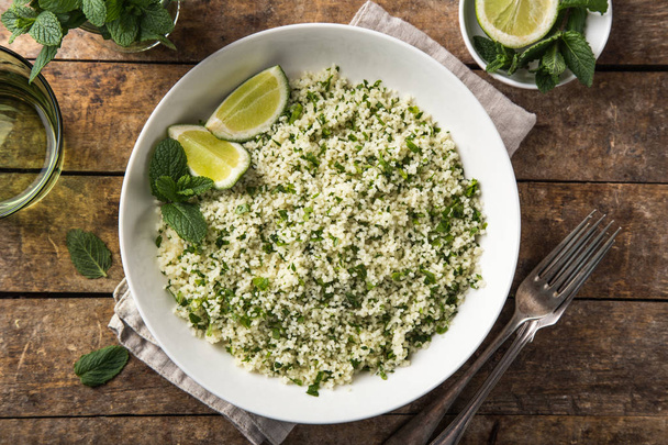 couscous with lemon and herbs in white bowl, wooden background, top view - Fotó, kép