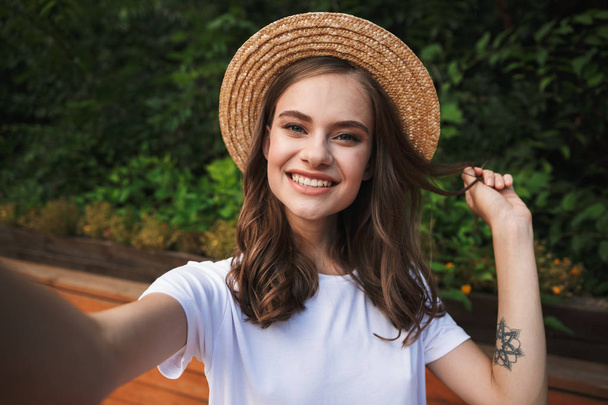 Smiling young girl taking a selfie with outsretched hand at the park outdoors - Foto, imagen