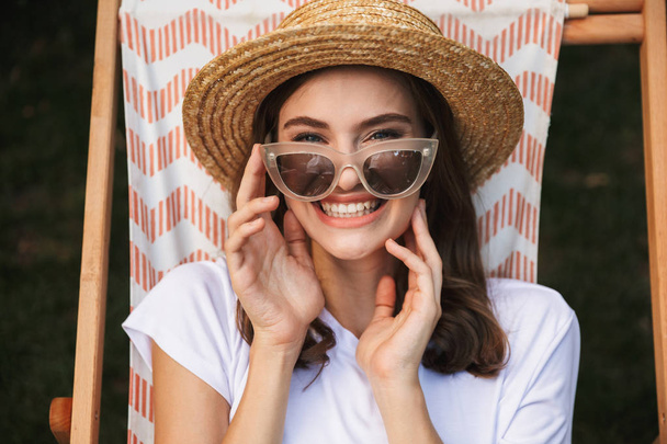 Cheerful young girl in sunglasses resting on a hammock at the city park outdoors in summer - Fotografie, Obrázek