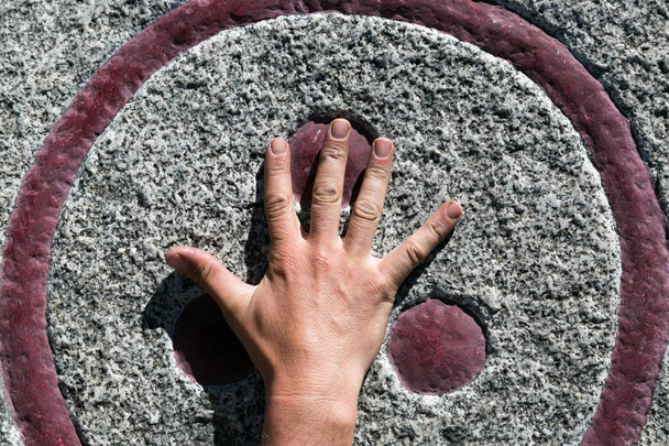The man's hand strokes the Symbol of peace and extraterrestrial civilization. Hand on the pagan symbol on the stone. - Valokuva, kuva