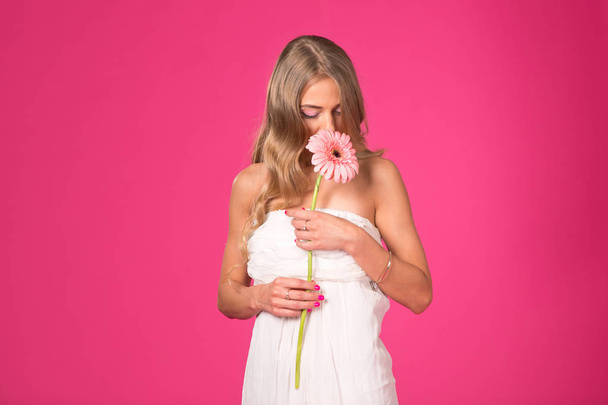 Beautiful woman on the pink background. Woman holding gerbera daisy flower. - Zdjęcie, obraz