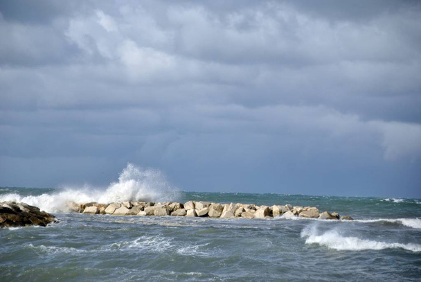 windy day at sea with big waves against rocks - Foto, Bild