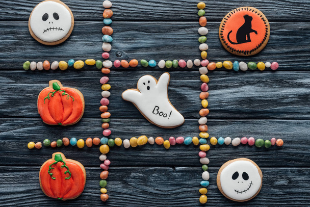 top view of composition from colorful candies and spooky halloween cookies on wooden table  - Foto, immagini