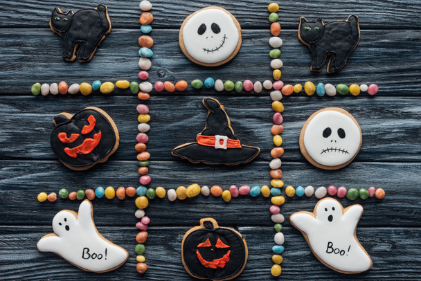 Widok z góry kompozycji z kolorowe cukierki i ułożone Halloweenowych ciasteczek na drewnianym stole  - Zdjęcie, obraz
