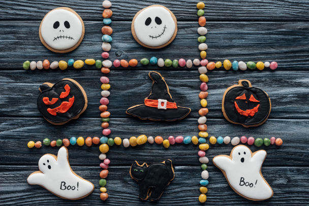 vista elevada de la composición de caramelos coloridos y galletas dispuestas de halloween en la mesa de madera
  - Foto, imagen