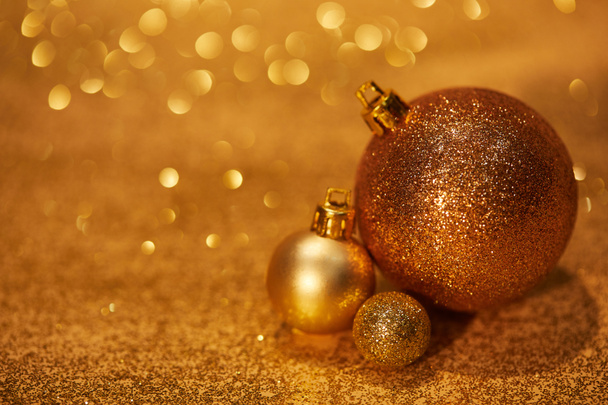 Χρυσή λαμπερά διακοσμητικά Χριστούγεννα μπάλες σε επιτραπέζια με πούλιες - Φωτογραφία, εικόνα