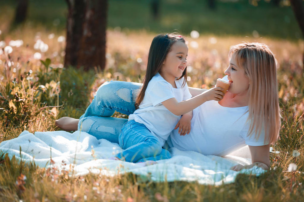 Boldog anya és lánya költés idő, zöld parkban, és eszik fagylaltot - Fotó, kép