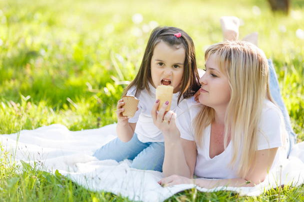 Happy mom and daughter. Walk in the green park Mother and little daughter ice cream nature - Foto, Bild