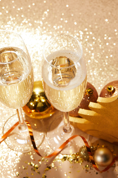 high angle view of christmas balls and two glasses of champagne with glitter on tabletop - Photo, image