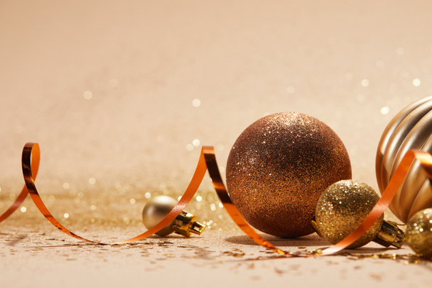 close up of glittering bright christmas balls and wavy ribbon on beige tabletop - Photo, Image