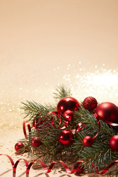 red sparkling christmas toys, wavy ribbon and pine branch on glittering surface - Photo, Image