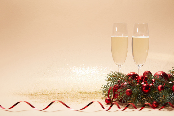 verres de champagne, boules de Noël lumineuses et branche de pin sur le dessus de table brillant
 - Photo, image