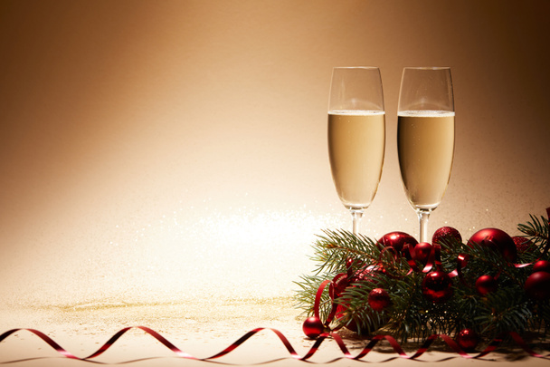 glasses of champagne, christmas balls and pine branch on glittering tabletop - Photo, Image