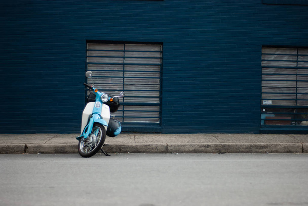 Scooter azul estacionado frente a una pared azul
 - Foto, imagen