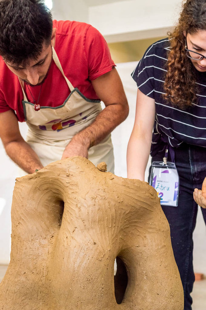 Two young Caucasian students working on a sculpture in an atelier - Photo, Image
