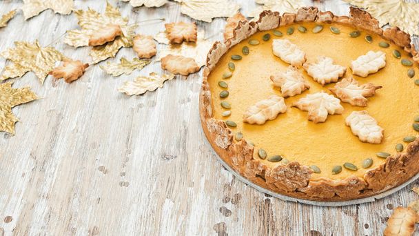 Homemade Spicy Pumpkin Pie decorated with cookies for Thanksgiving or Halloween on wooden rustic table. Traditional autumn sweet dessert, golden leaves - Photo, Image