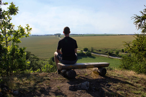 Молодой человек сидит на скамейке на природе смотровой, Чешский пейзаж
 - Фото, изображение