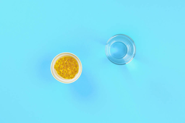 Swallowing tablets. Pills and a glass of water against a blue table background. Top view, copy space, flat lay - Фото, изображение