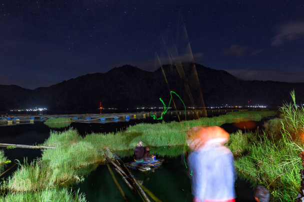 kintamani, indonesien - 1. juni: unbekannter fischer warf am 1. juni 2017 im danau batur see in der nähe von mount batur in kintamani, indonesien, in der nacht glühen in die dunklen köder. - Foto, Bild