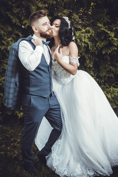 beautiful bride is kissing the groom on the cheek during a wedding walk - Valokuva, kuva