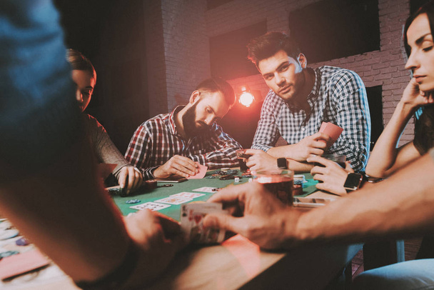 Young Friends Playing Poker on Party at Home. Playing Games. Indoor Fun. Young Girl. Young Guy. Sitting at Table. Party with Friends. Indoor Activities Concept. Gambling. Card Games. - 写真・画像