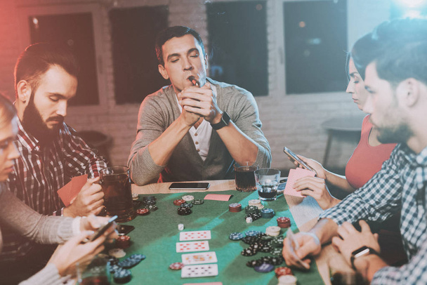 Young Friends Playing Poker on Party at Home. Playing Games. Indoor Fun. Young Girl. Young Guy. Sitting at Table. Party with Friends. Indoor Activities Concept. Gambling. Card Games. - 写真・画像