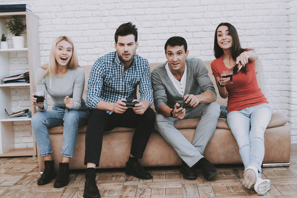 Young People Playing Videogames on Party at Home. Eating Snacks. Indoor Fun. Young Girl. Young Guy. Sitting on Sofa. Party with Friends. Indoor Activities Concept. Console Gaming Concept. - Foto, Imagen