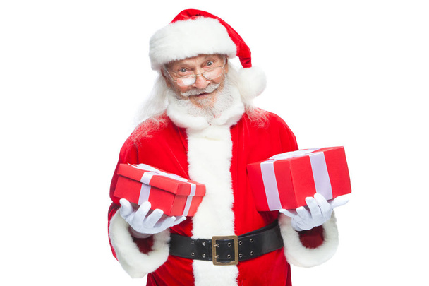 Christmas. Smiling Santa Claus in white gloves holds two boxes with gifts. The concept of choosing a gift, generous gifts. Isolated on white background. - Fotó, kép