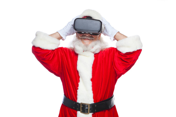 Christmas. Santa Claus in black virtual reality glasses makes gestures with his hands. Surprise, emotion. New technology. Isolated on white background. - Foto, Imagen