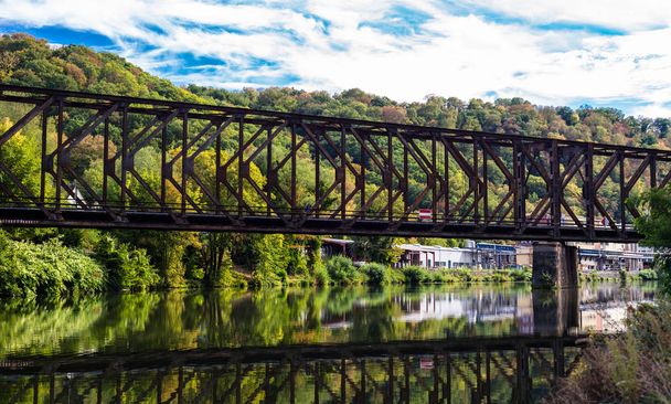 Az erdő, fák, őszi színek a háttérben folyó csatornán fém vasúti híd. - Fotó, kép