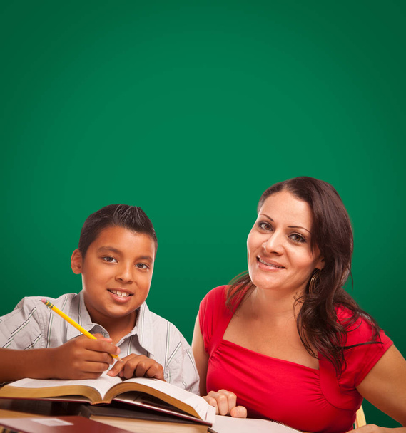 ヒスパニック系の少年と女子大人勉強の後ろに空白のチョーク ボード. - 写真・画像