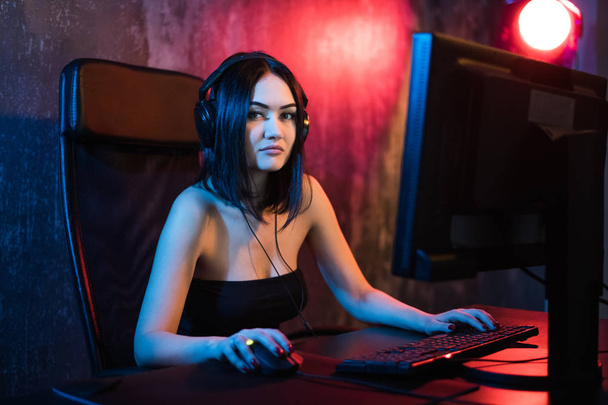 彼女のパーソナルコンピュータ上で一人称シューティングオンラインビデオゲームで遊んで美しいプロゲーマーの女の子。メガネと笑顔を身に着けてカジュアルなかわいいギーク。サイバーeスポーツインターネット選手権. - 写真・画像