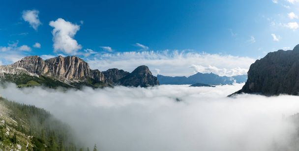 panorámás hegyi táj, a Val Gardena-ban az olasz Dolomitok, a hegyi csúcsok és a vastag felhőzet, a völgyekben, alatta egy kék ég késő ősszel - Fotó, kép