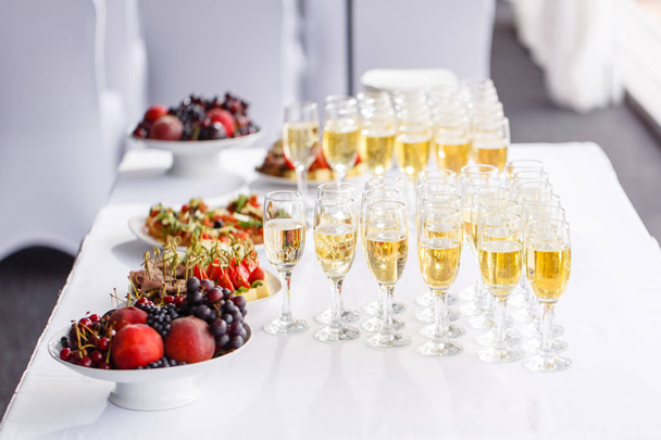 Un montón de copas de champán o vino en la mesa en el restaurante. mesa buffet con un montón de deliciosos bocadillos
. - Foto, imagen