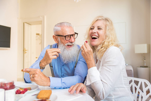 Happy senior couple having breakfast at home - Married couple on the 60's in their apartment, concepts about senority and relationship - Φωτογραφία, εικόνα