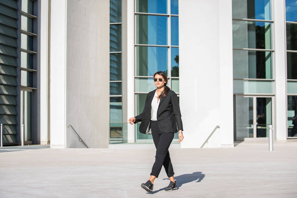 Beautiful businesswoman walking outdoors - Pretty young adult female - Фото, изображение