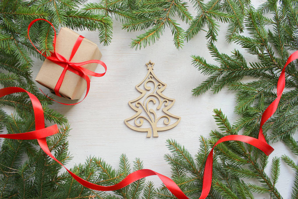Karácsonyi háttér. Zöld fa ágai keret fehér fa háttér, díszdobozban, piros szatén szalag, kézzel készített karácsonyi fa, a karácsony összetétele szünet feldíszítés. Fehér hópelyhek és a hó. Másolás spacen - Fotó, kép